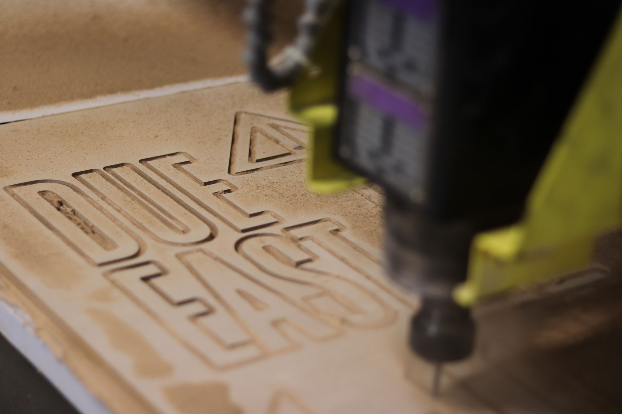 Picture of the CNC machine cutting out the lettering for the wood sign.