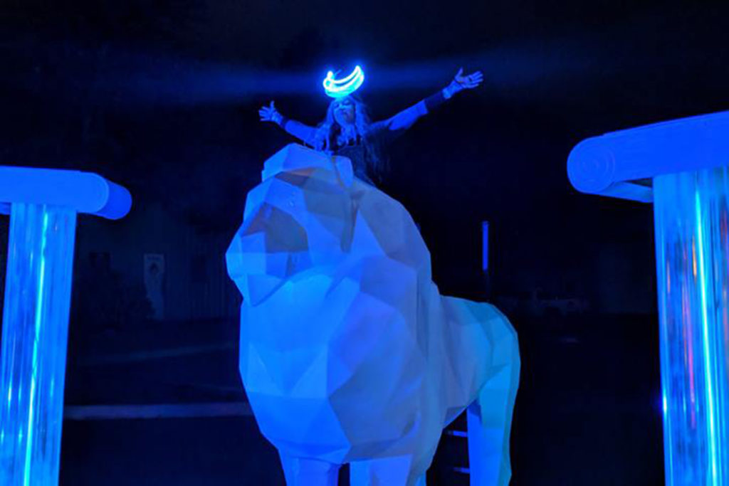 Picture of a festival goer atop a foam carved lion with blue lighting.