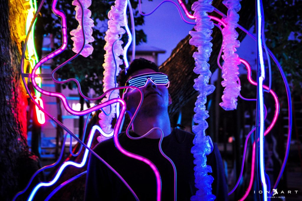 Picture of an attendee surrounded by neon light tubes.