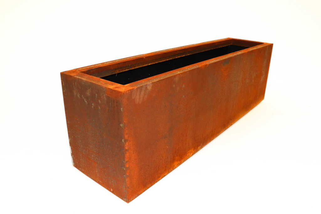 Picture of a rustic steel trough planter with a white backdrop.