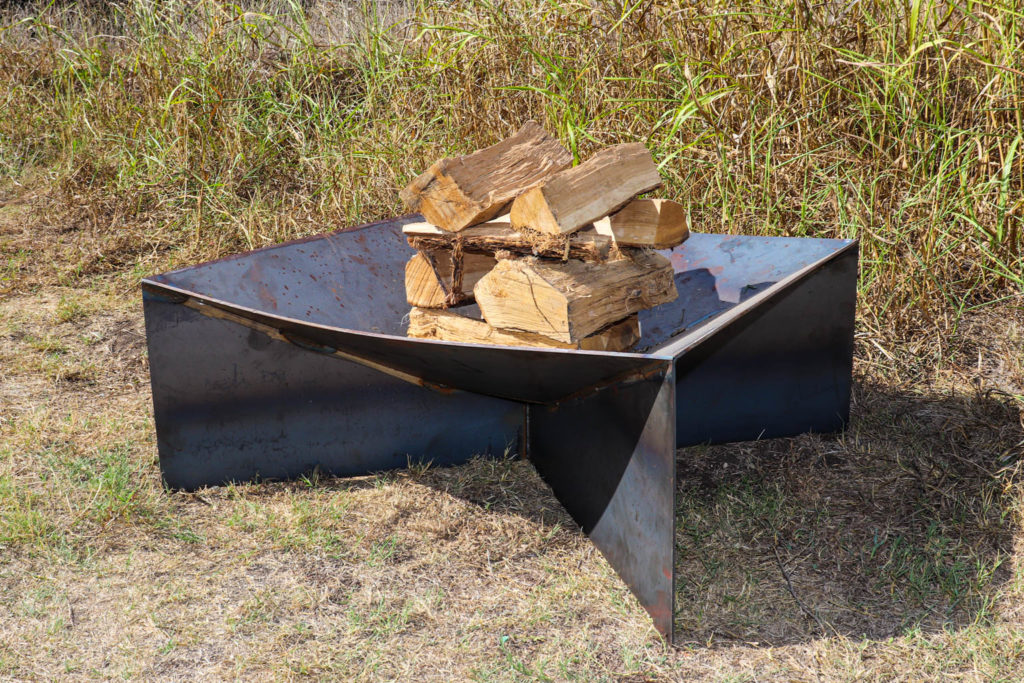 Picture of steel fire pit with fire wood inside the bowl.