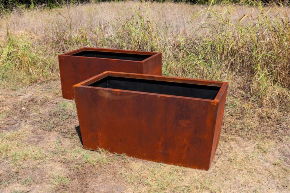 Picture of a rustic steel planter with tapered edges and a rustic steel planter with straight edges in a Texan field.