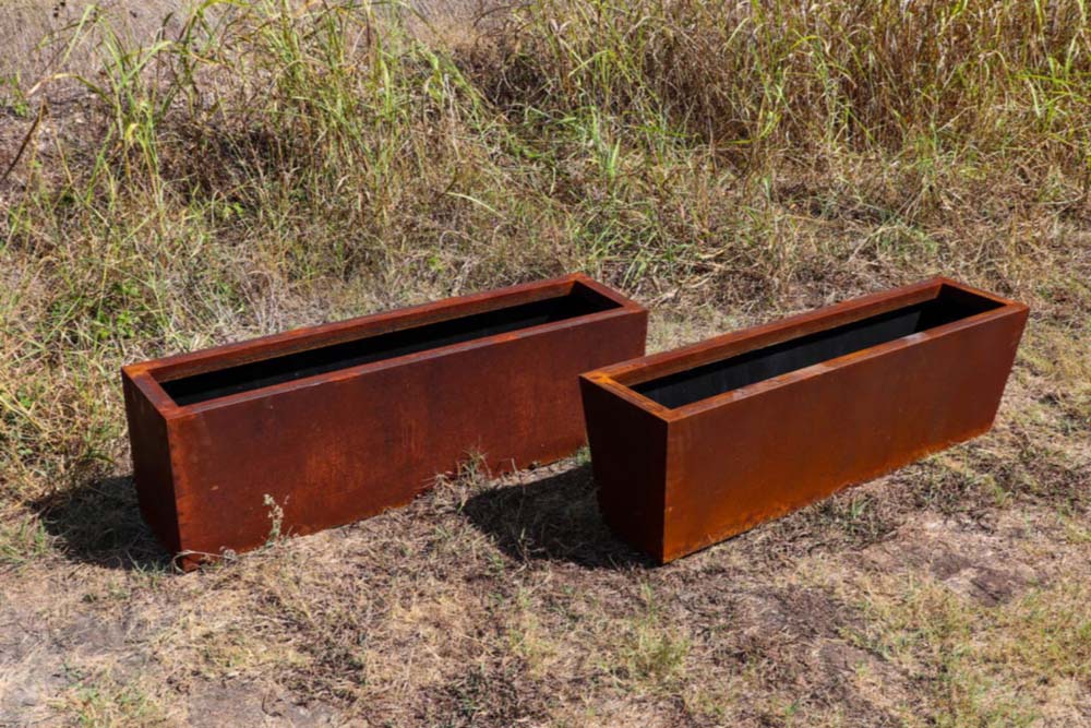 Picture of a rustic steel trough planter with straight edges & a rustic steel trough planter with tapered edges in a Texan field.