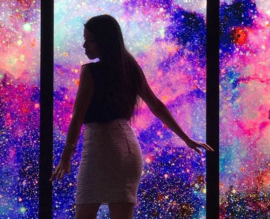 Picture of a girl's silhouette in front of a glowing vinyl galaxy print.