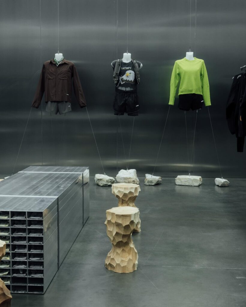 Interior of trade show booth depicting clothing on mannequin bodies and stools